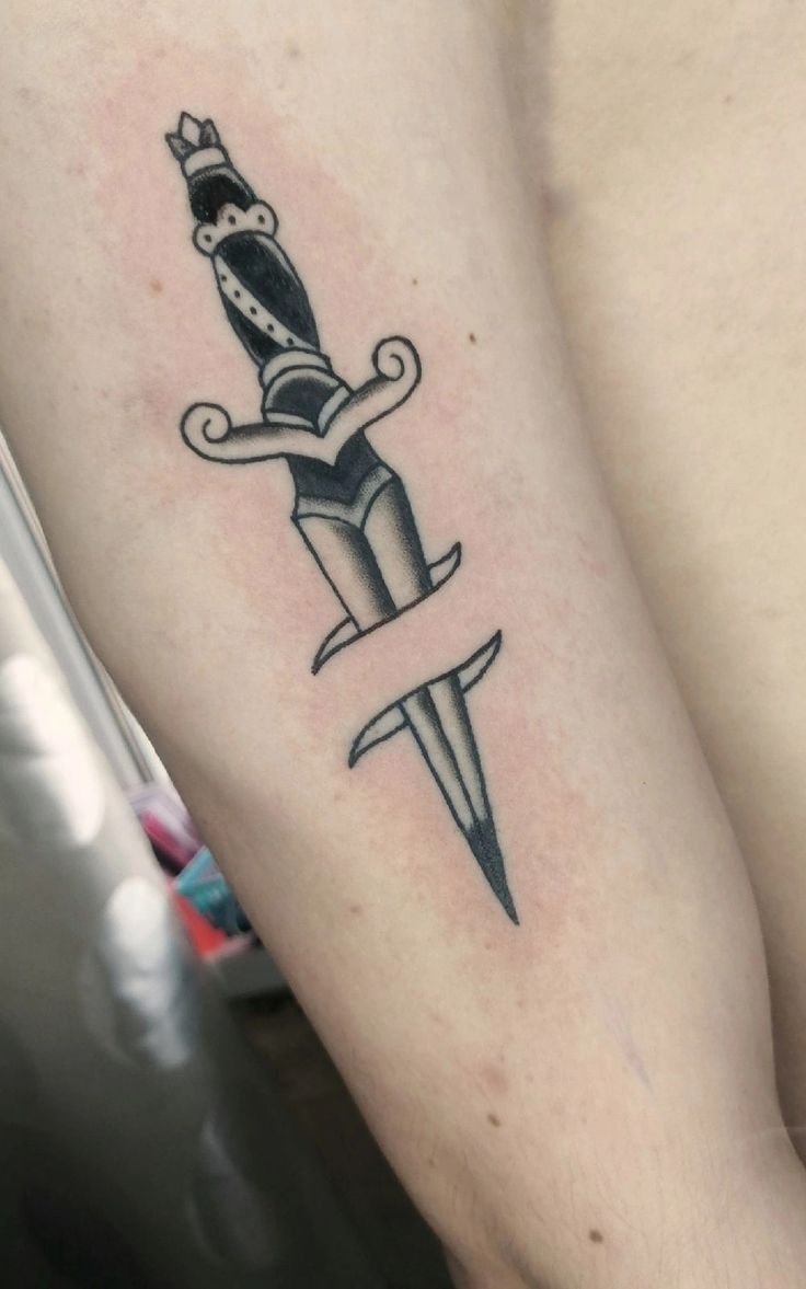 a tattoo on the arm of a person holding a knife