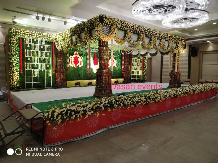 a decorated stage set up for an event with flowers and greenery on the floor