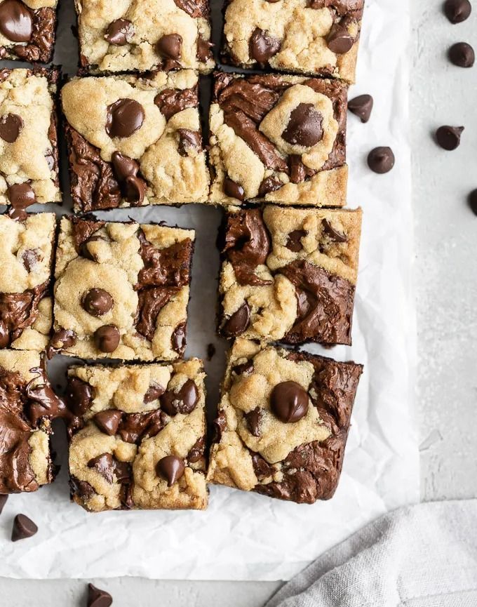 chocolate chip cookie bars cut into squares on top of parchment paper and scattered with chocolate chips