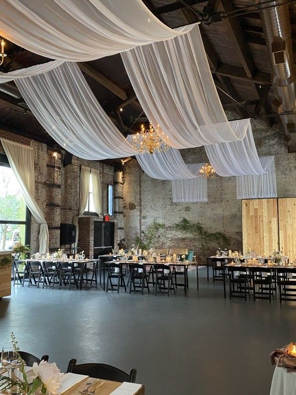 a large room with tables and chairs covered in white draping over the ceiling