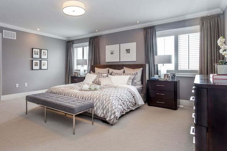 a bedroom with gray walls and carpeted flooring has a large bed in the center