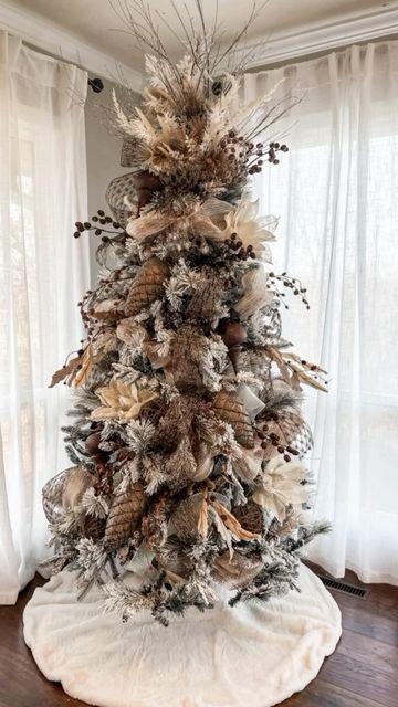 a decorated christmas tree in the corner of a room with white curtains and wooden floors