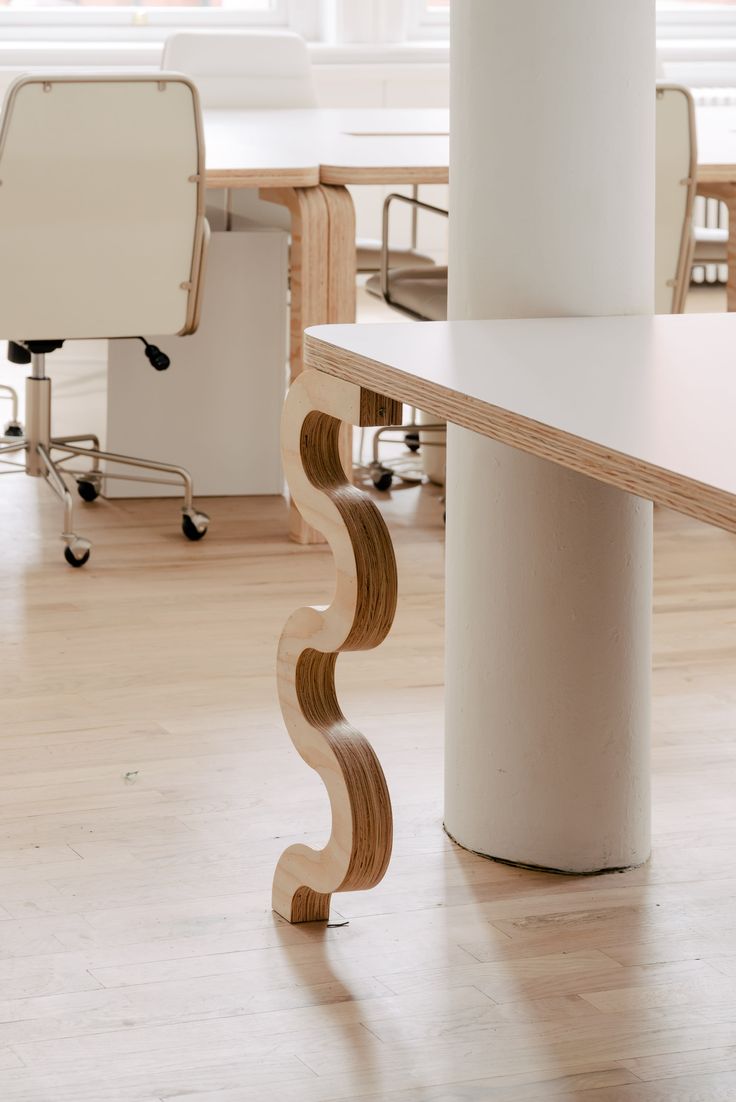 an office with white desks and chairs in the background, along with a curved wooden table