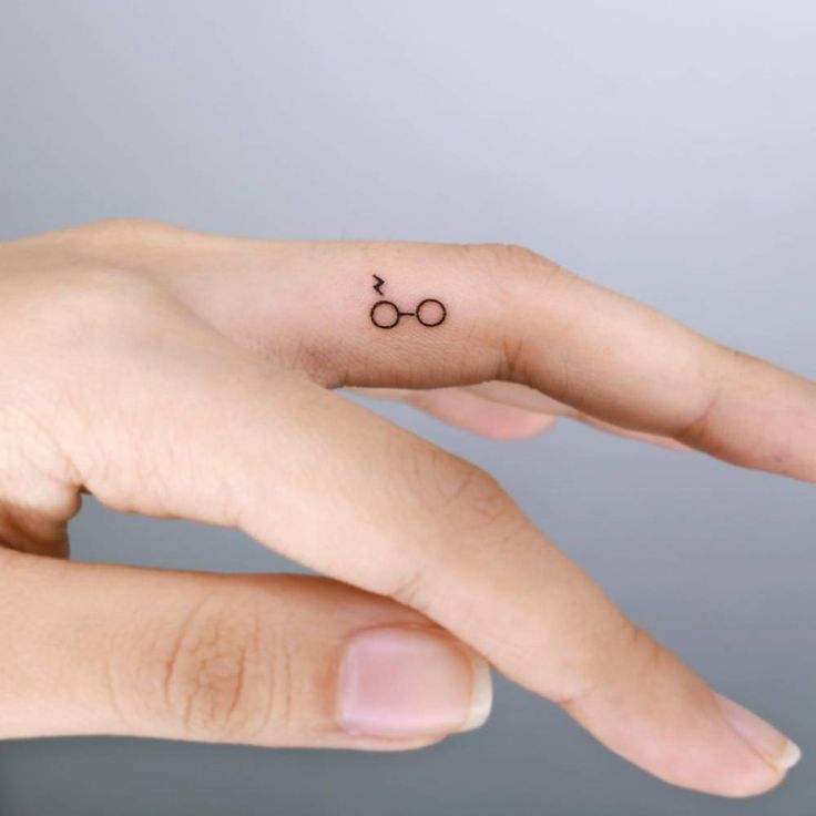 a person's hand with a tiny harry potter ring tattoo on it, and the symbol for her