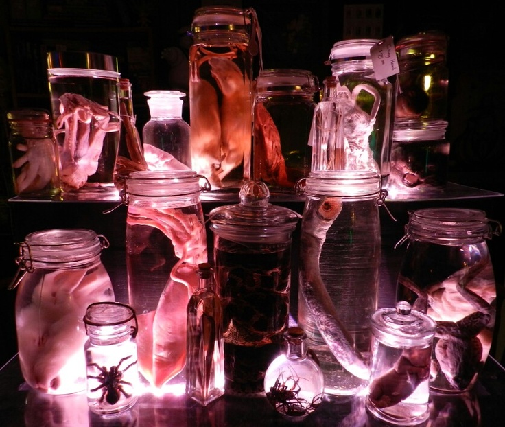 many jars filled with different types of items on top of a black table in the dark