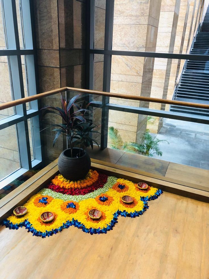 a plant is sitting on the floor in front of a window with an artistic rug