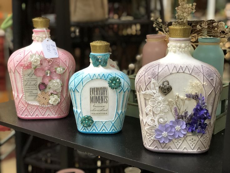 three different colored bottles sitting on top of a table next to each other with flowers in them