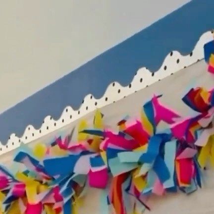 colorful streamers are hanging from the ceiling in front of a blue and white wall