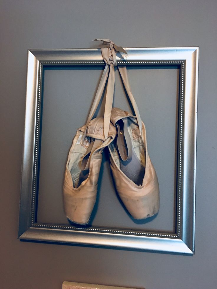 two pairs of ballet shoes hanging on a silver frame