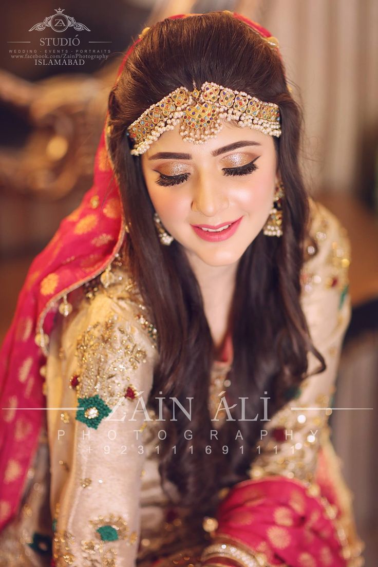 a woman in a red and gold bridal outfit sitting down with her eyes closed