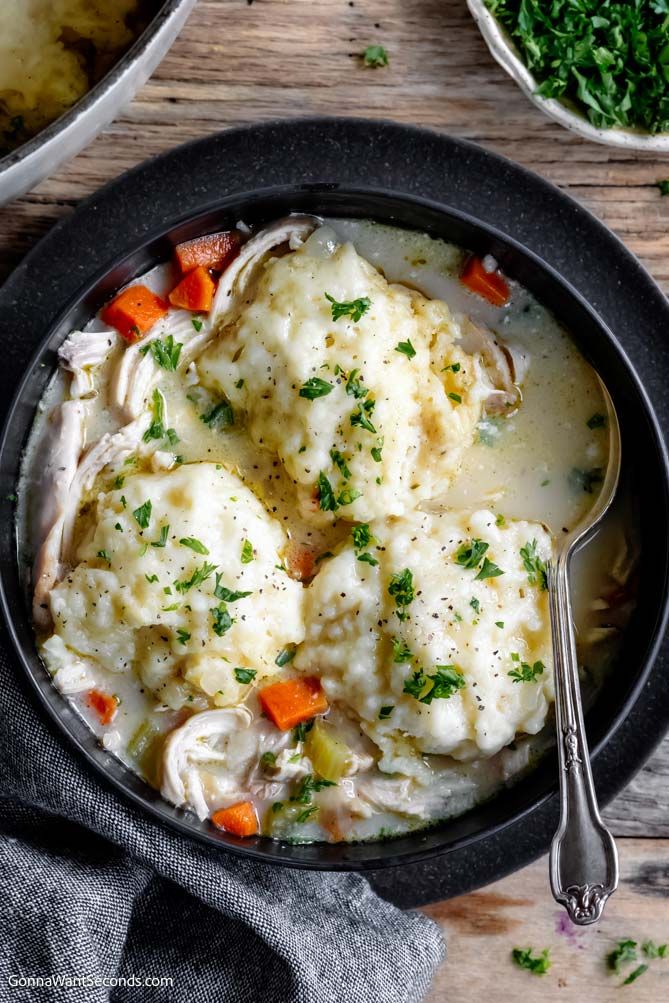 a bowl filled with chicken and dumplings on top of a wooden table