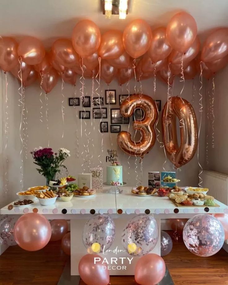 a table topped with balloons and desserts next to a number 30 sign on the wall