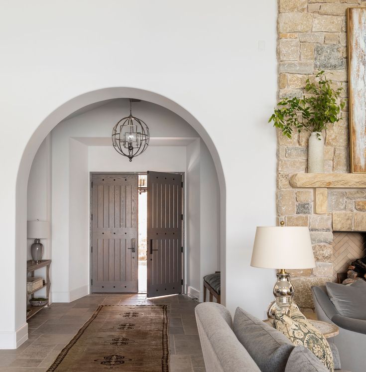 an archway leading to a living room and dining area with two couches, a lamp, and a fireplace