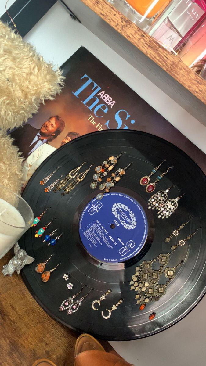 a teddy bear sitting next to a record on a table with other items around it