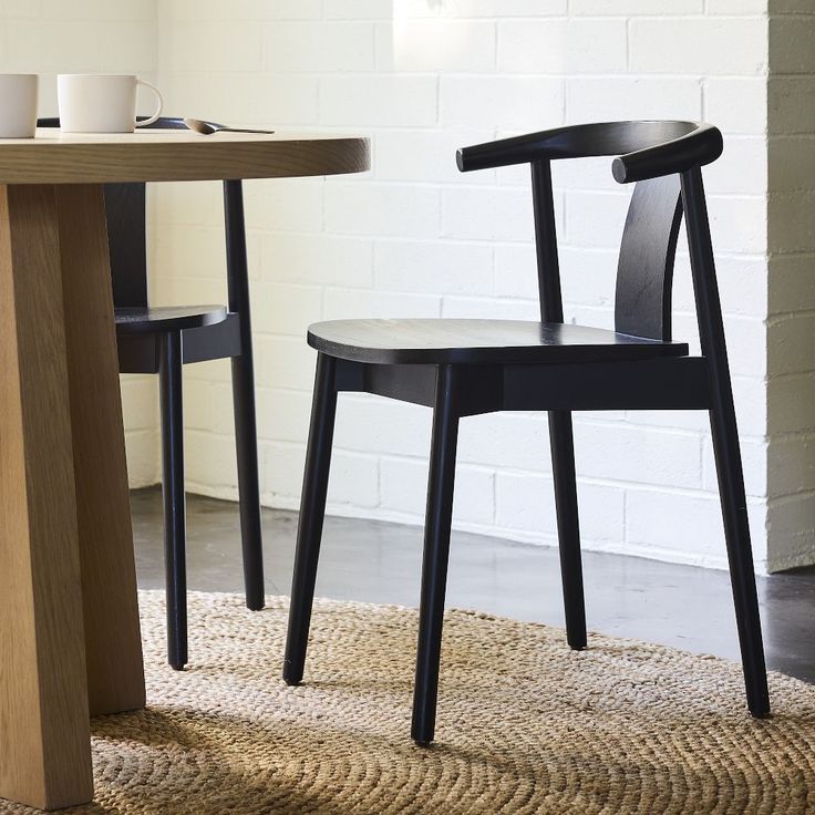 two black chairs sitting on top of a rug next to a wooden table and chair