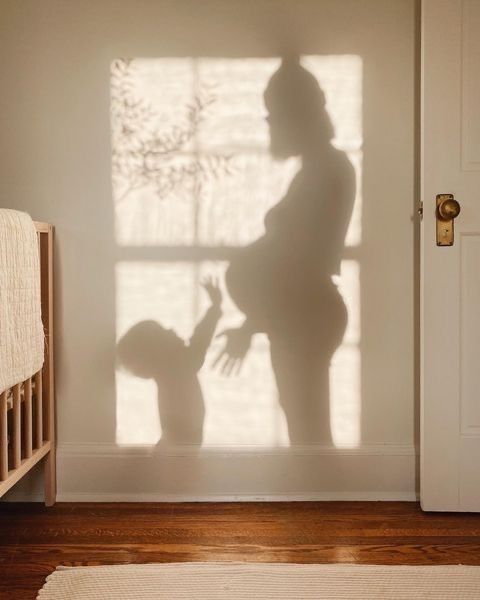 a shadow of a woman holding a baby in her arms and standing next to a crib