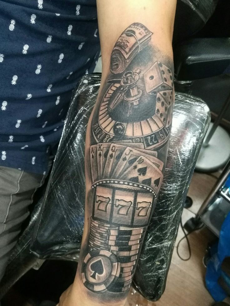 a man's arm with a clock and playing cards tattoo on the left forearm