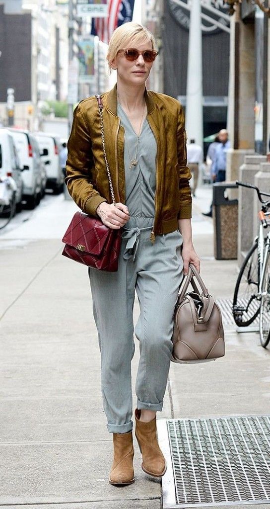 a woman is walking down the street with her purse and handbag in one hand