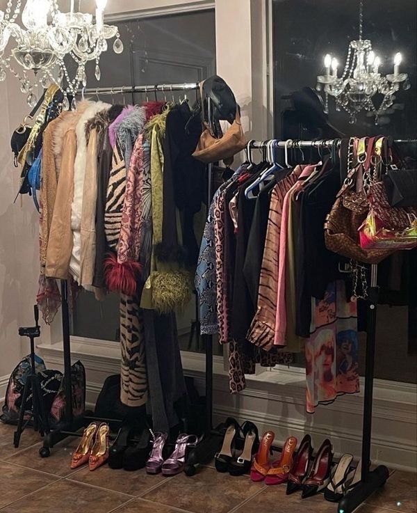 clothes and shoes are hanging on racks in front of a window with chandelier