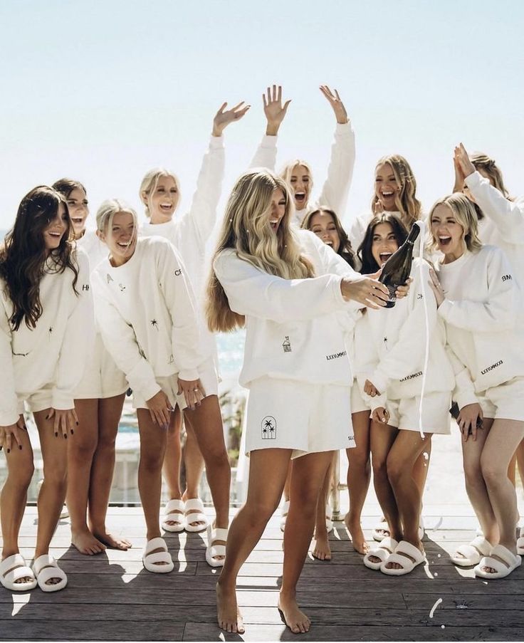 a group of women standing on top of a wooden floor next to each other wearing white outfits