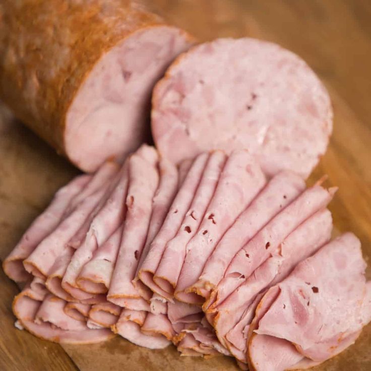 sliced ham sitting on top of a wooden cutting board