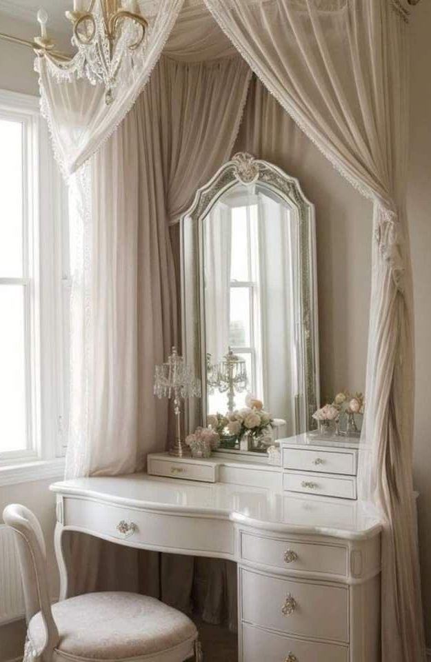 a white dressing table with a mirror, stool and chandelier