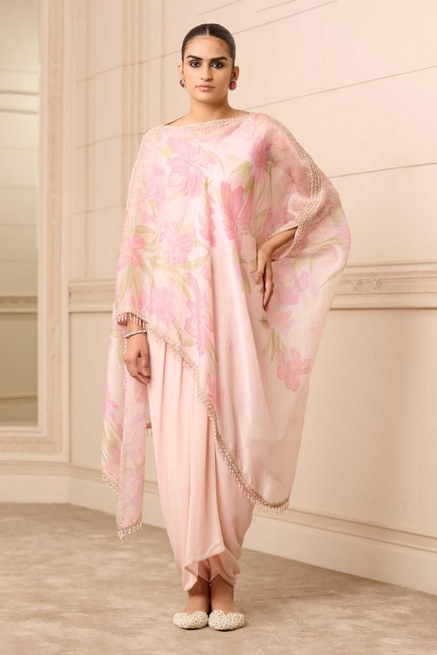 Pink, mauve asymmetric kaftan top in satin organza base with all-over floral print and an embroidered border and pearl tassels. Comes with a jersey slip inside and georgette dhoti pants.
Components: 3
Pattern: Print
Type Of Work: Floral
Neckline: Boat
Sleeve Type: Flared Sleeves
Fabric: Dhoti : Georgette, Slip : Jersey and Kaftan : Satin Organza
Color: Purple,Pink
Other Details: 
Asymmetrical kaftan top hem
Crystal bead drops
Occasion: Destination Wedding - Aza Fashions Silk Palazzo Set With Traditional Drape For Reception, Bollywood Style Silk Palazzo Set For Evening, Silk Floor-length Sets With Draped Sleeves, Festive Silk Sets With Draped Sleeves, Silk Sets With Draped Sleeves For Festive Occasions, Silk Palazzo Set With Traditional Drape For Evening, Silk Palazzo Set For Evening With Traditional Drape, Silk Palazzo Set With Sheer Dupatta For Reception, Evening Kurta With Sheer Dupatta