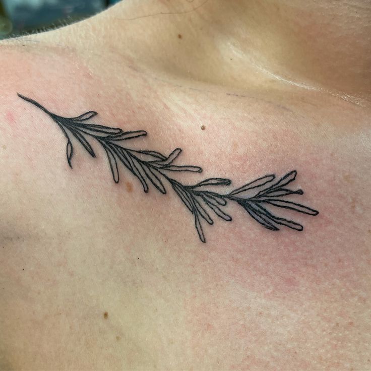 a black and white photo of a woman's chest with a branch tattoo on it