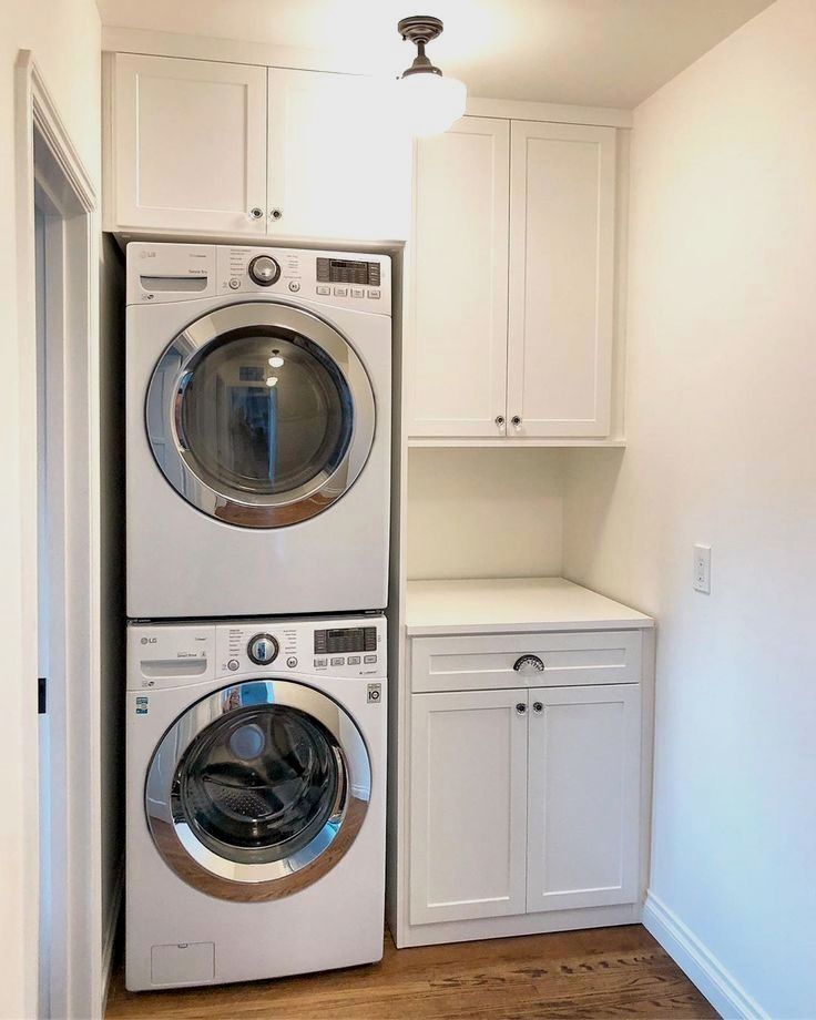 a washer and dryer are in the corner of this laundry room with white cabinets