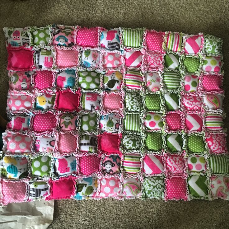 a blanket made out of many different types of fabric and buttons on the floor next to a pair of scissors