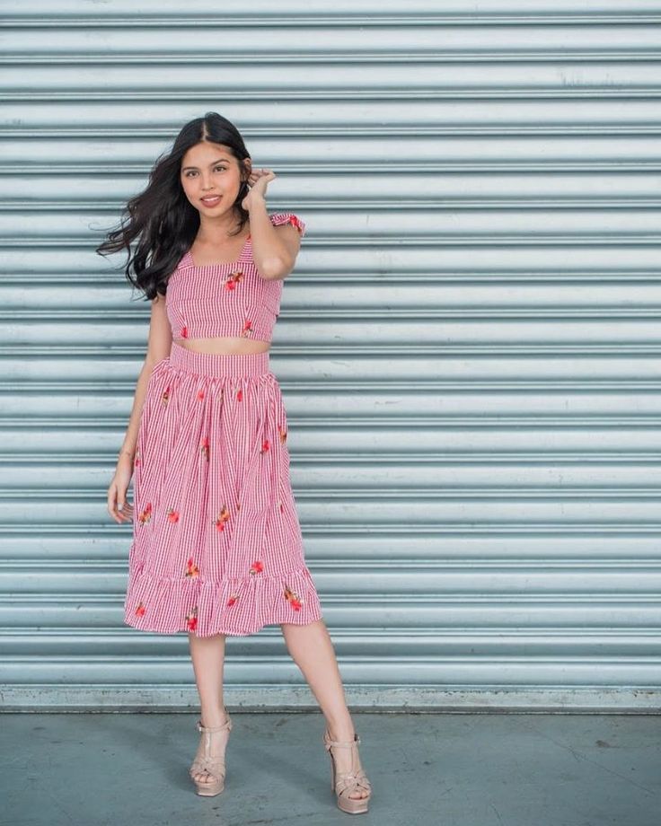 a woman standing in front of a garage door wearing a pink and white striped dress