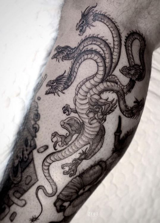 a black and white photo of a dragon tattoo on someone's left arm,