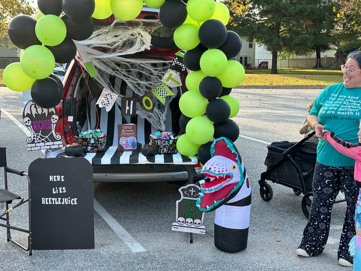 some people are standing in front of a truck with balloons and decorations on the back