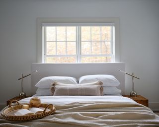 a bed with white sheets and pillows in front of a window