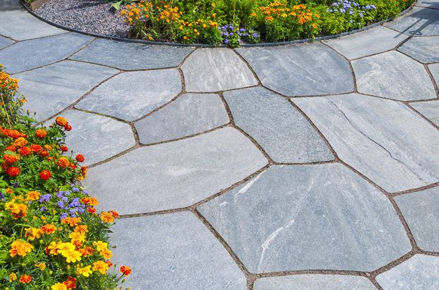 a stone walkway surrounded by colorful flowers