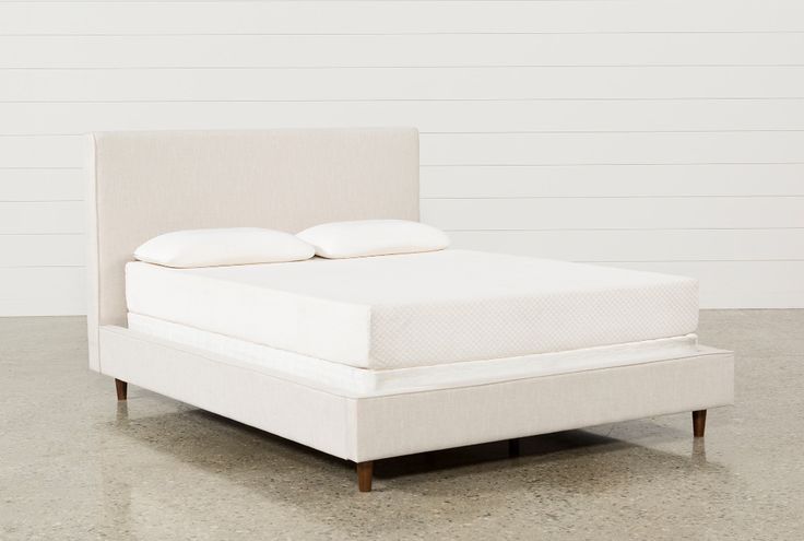 a white bed with two pillows on top of the headboard and foot board, in front of a white wall