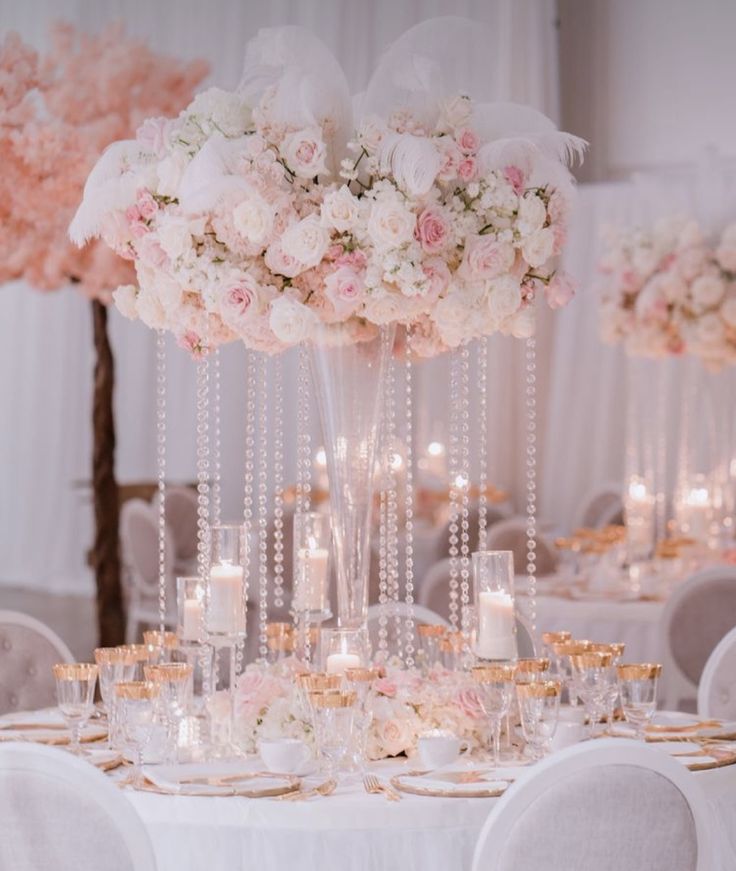 a table with white and pink flowers, candles and chandeliers in the center