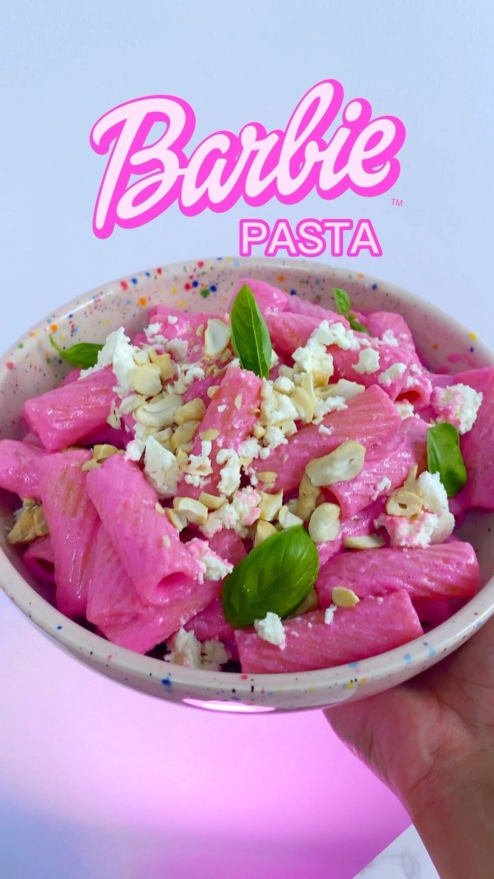 a person holding up a bowl of food with feta and basil on it, in front of the barbie logo