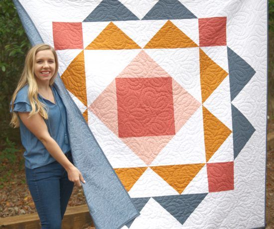 a woman standing next to a large quilt