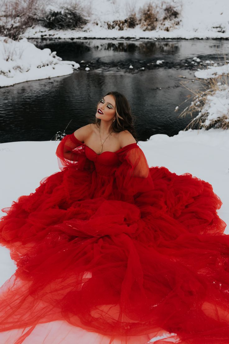 a woman in a red dress sitting on the snow