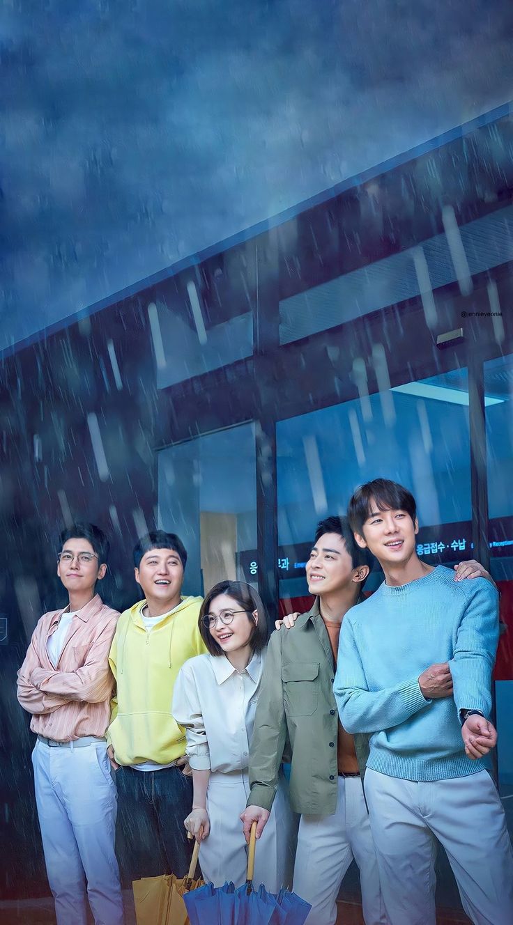 four people standing in front of a building with an umbrella and rain falling down on them