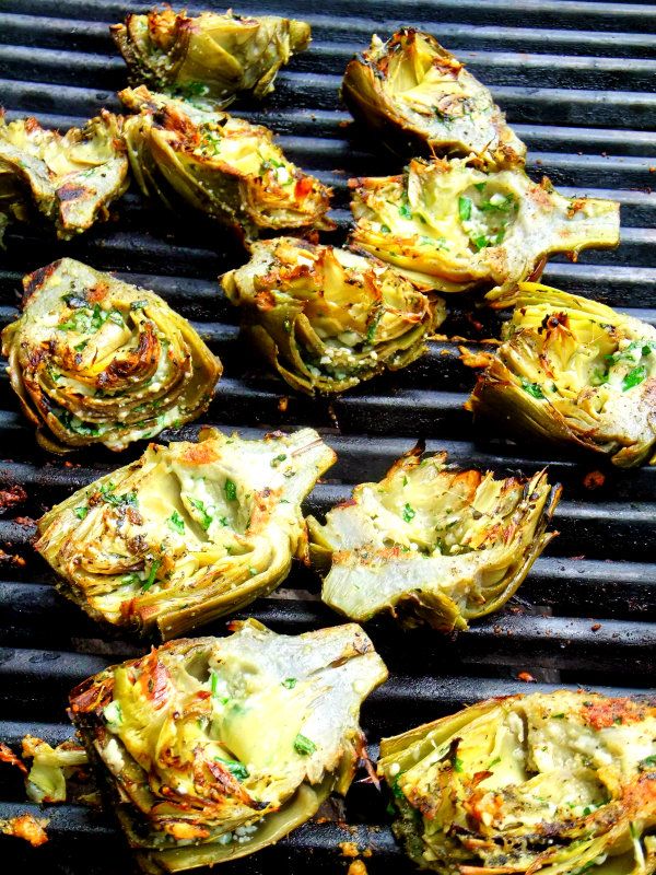 grilled artichokes are being cooked on a grill with other food items