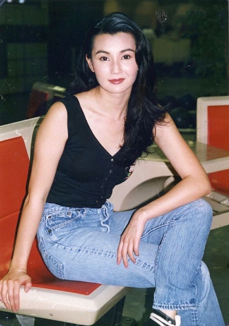 a woman sitting on top of a white bench next to a window with red trim