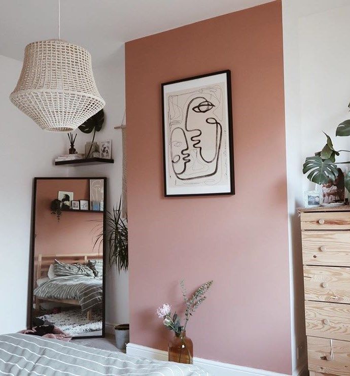 a bedroom with a bed, mirror and plant on the wall in front of it