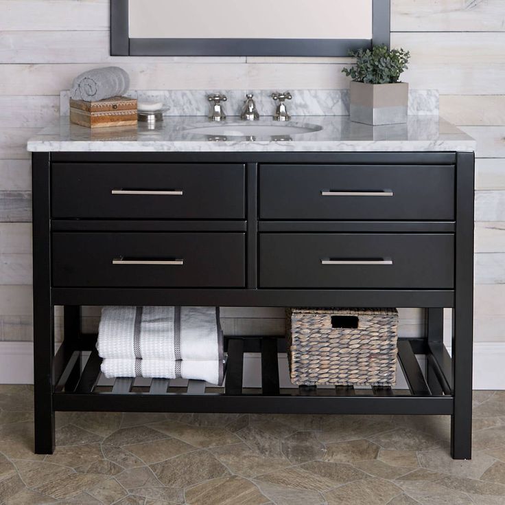 a bathroom vanity with marble top and two drawers under a large mirror over the sink