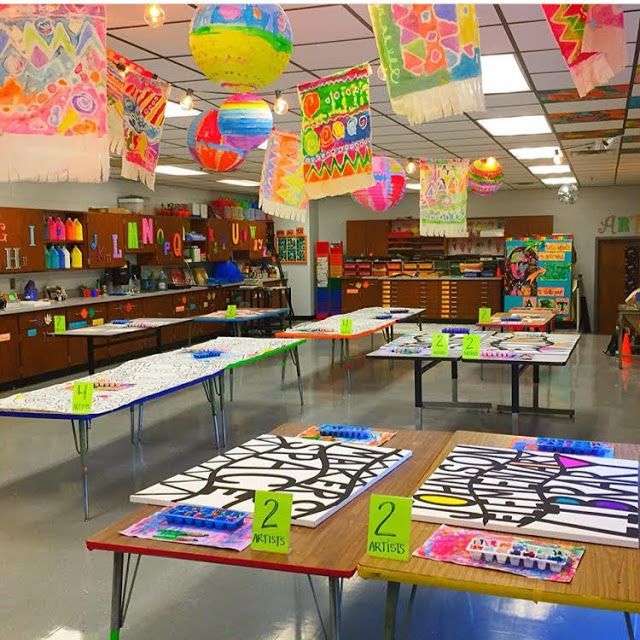 a classroom filled with lots of desks covered in paper decorations and hanging from the ceiling