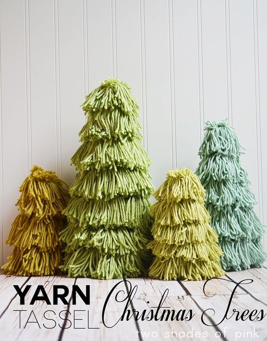 three yarn christmas trees sitting next to each other on a wooden table with text overlay that reads yarn tassel christmas trees