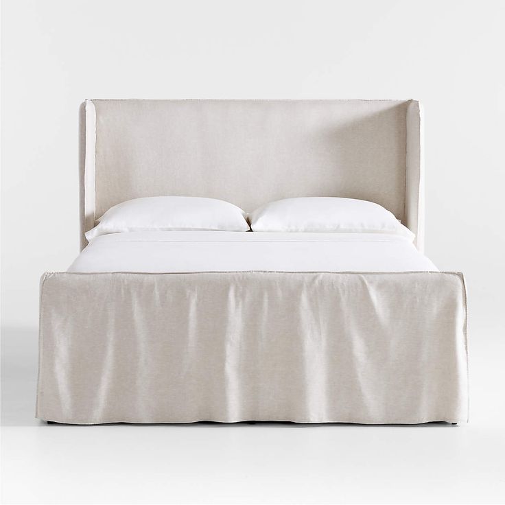 a white bed with two pillows on top of it