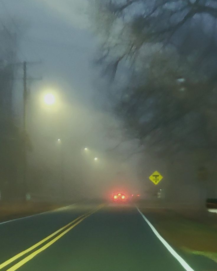 a foggy street with cars driving down it