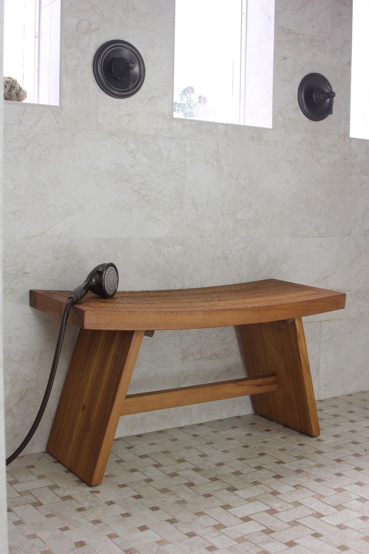 a wooden bench sitting on top of a tiled floor next to two windows with light coming from them